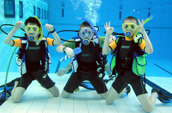 Young divers practising scuba skills in a swimming pool with instructor supervision